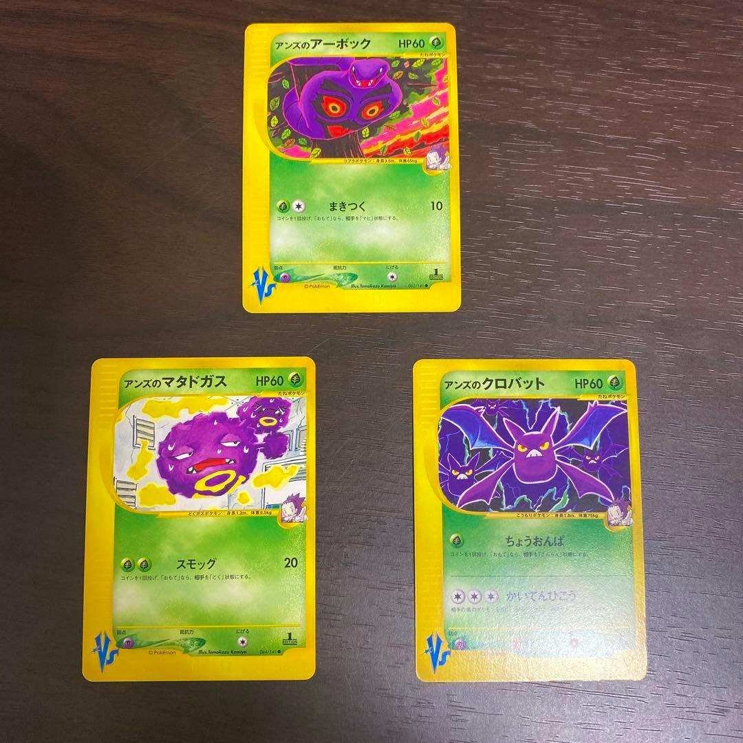 Fronts of three Pokémon trading cards (アーボック, マタドガス, クロバット) laid on a dark surface.