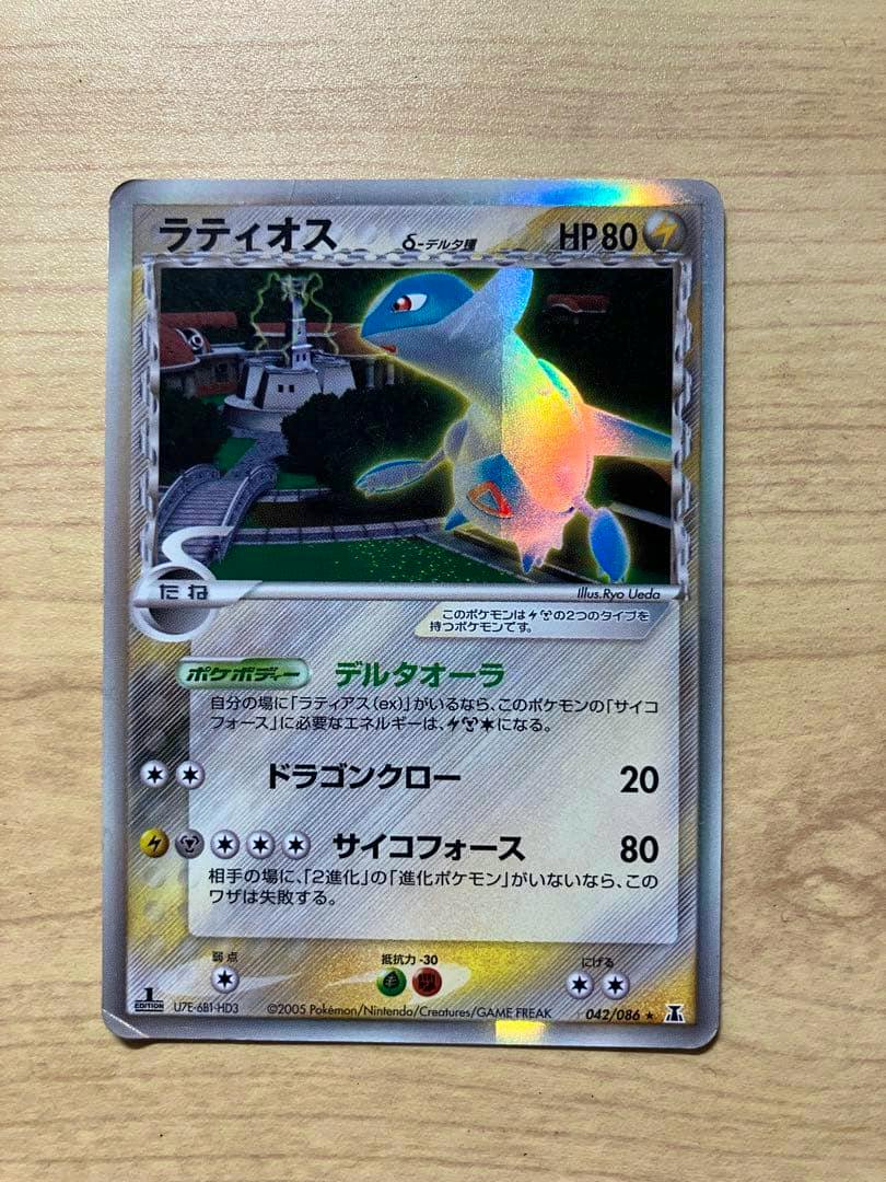 Front of the ポケモンカード ラティオス デルタ種 1ED 042/086 ホロ trading card lying on a wooden surface.