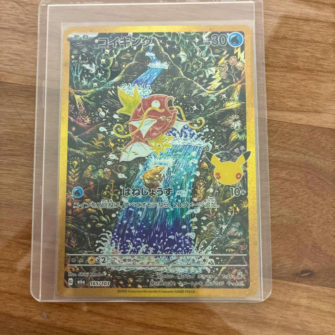 Photo of the Pokémon trading card コイキング (165/103) in a protective sleeve on a wooden surface.