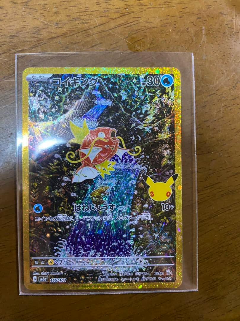 Front of a holographic Pokémon コイキング (Magikarp) trading card in a clear protective sleeve showing the foil artwork and Japanese text.