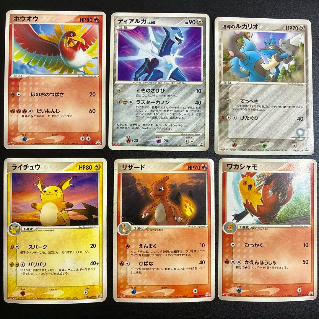 Photo of six Japanese Pokémon trading cards from a Meiji promotional set arranged in two rows of three on a dark surface.