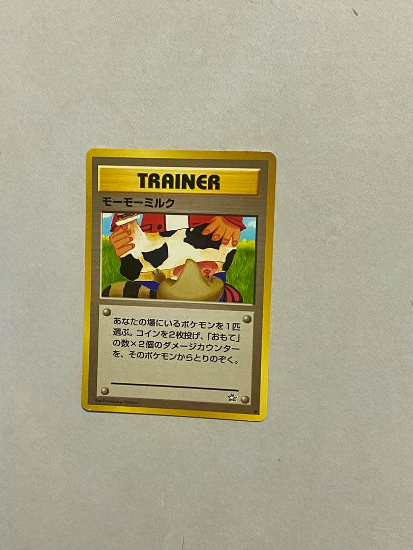 Front of a Japanese 'モーモーミルク' Trainer Pokémon trading card showing the card art and Japanese text on a light background.