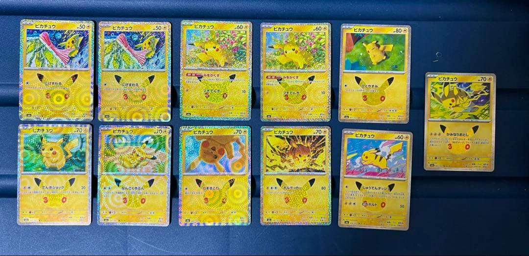 Eleven Pikachu Pokémon trading cards arranged in rows on a dark surface.