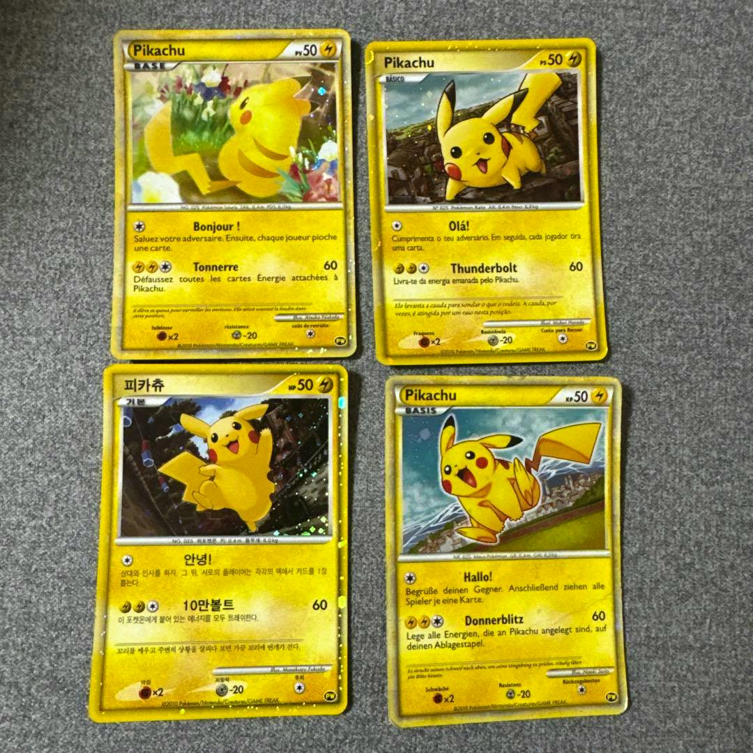 Four Pikachu Pokémon trading cards laid out in a 2x2 grid on a gray surface showing the front faces of the cards.
