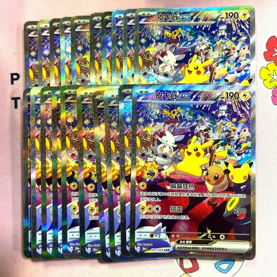 Multiple holographic Pokémon Pikachu ex trading cards overlapped in a fanned layout on a pink cloth background.