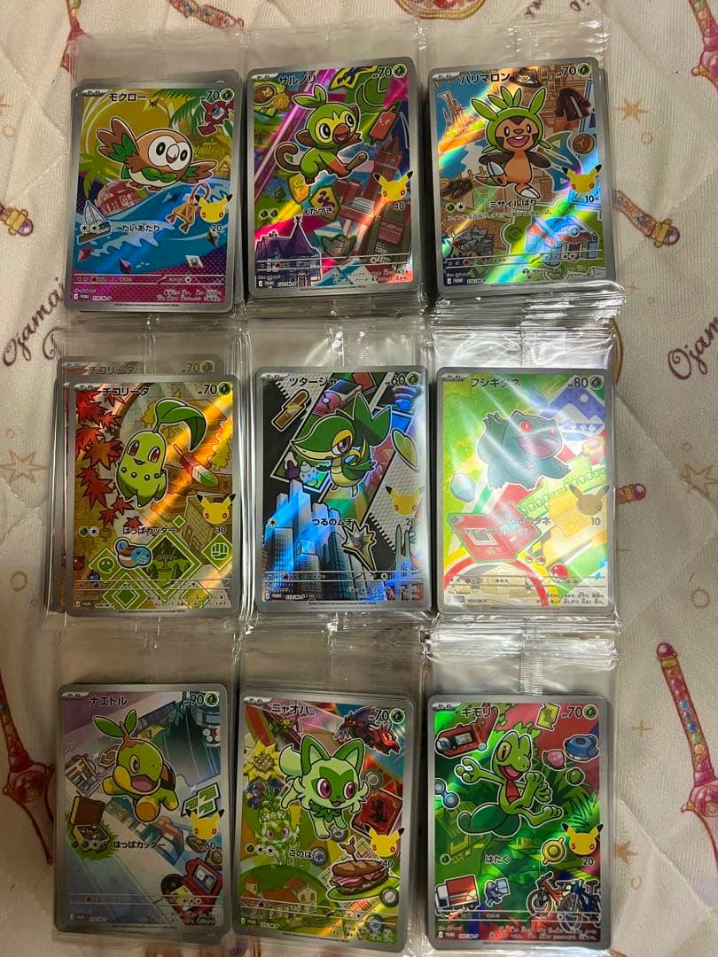 Photo of stacks of Pokémon promo trading cards in clear protective sleeves arranged on a patterned blanket.