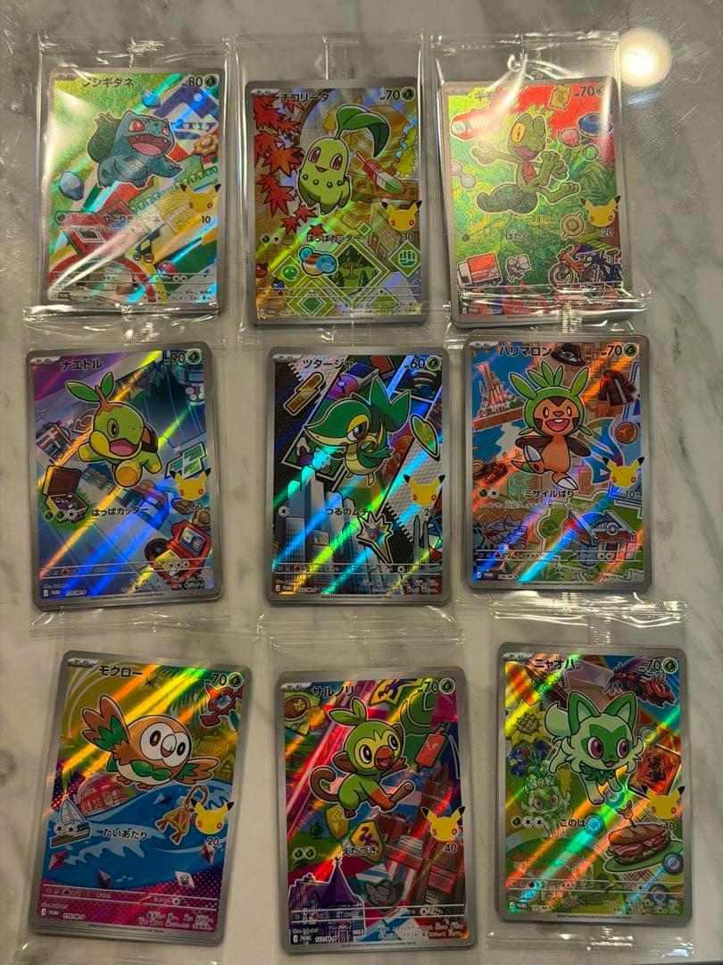 Nine holographic Pokémon promo trading cards featuring starter Pokémon in protective sleeves arranged in three rows on a marble surface.