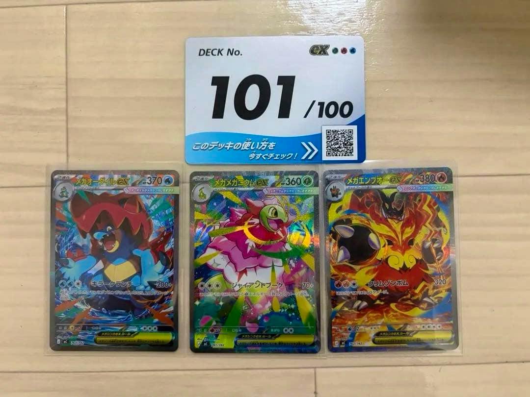 Three Pokémon trading cards in sleeves laid on a wooden floor with a 'DECK No. 101' card above them.