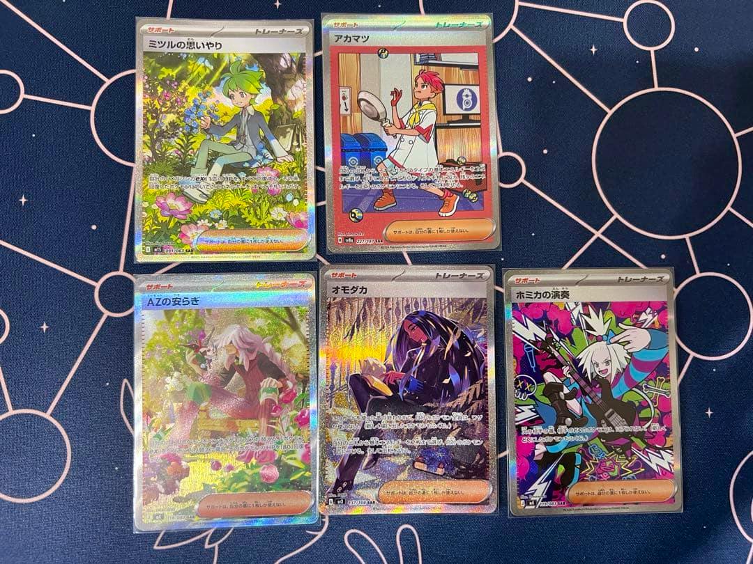 Six Pokémon supporter cards shown face-up in two rows on a patterned playmat.