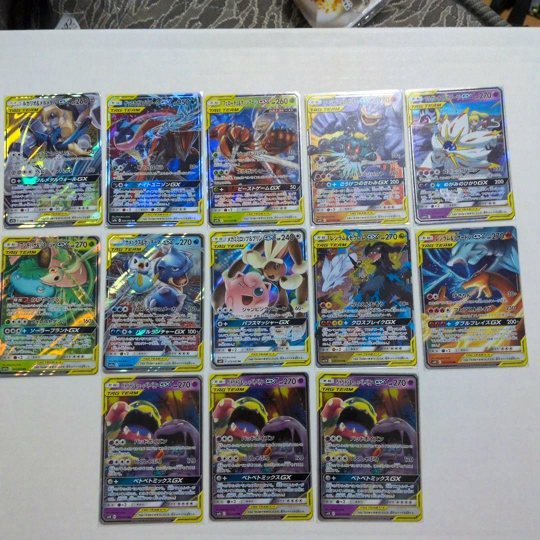 A set of 13 TAG TEAM GX Pokémon trading cards laid out on a white surface.