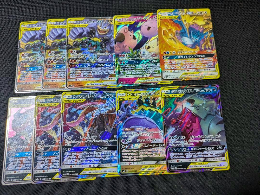 A spread of Pokémon TAG TEAM GX trading cards laid out on a dark textured surface, showing multiple holographic cards.