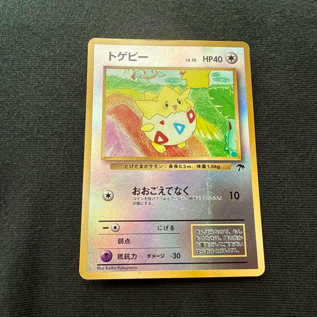 Front of the Togepi trading card with Japanese text and foil background on dark fabric.
