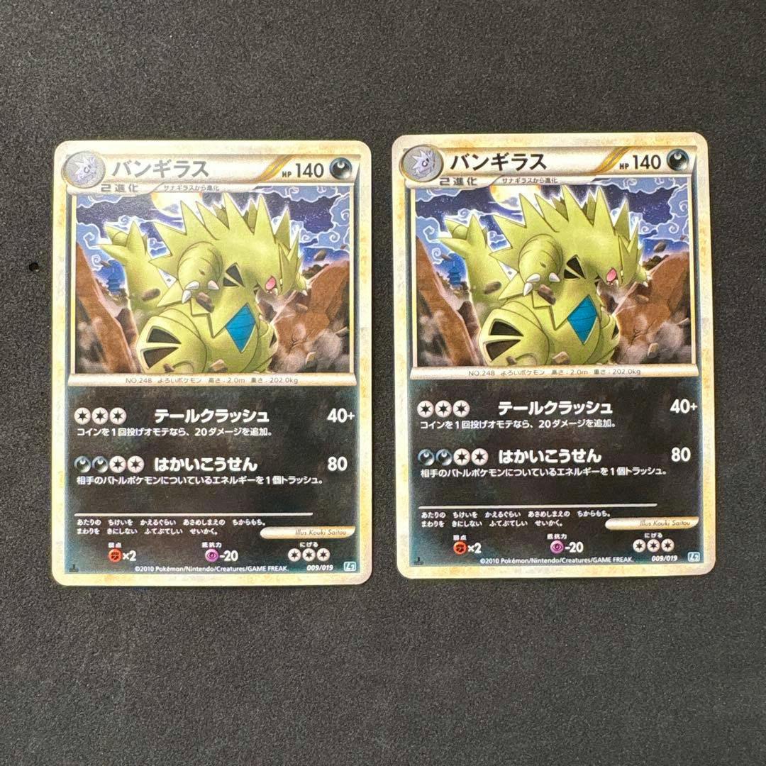 Two バンギラス (Tyranitar) Pokémon trading cards shown front-side on a dark textured background.