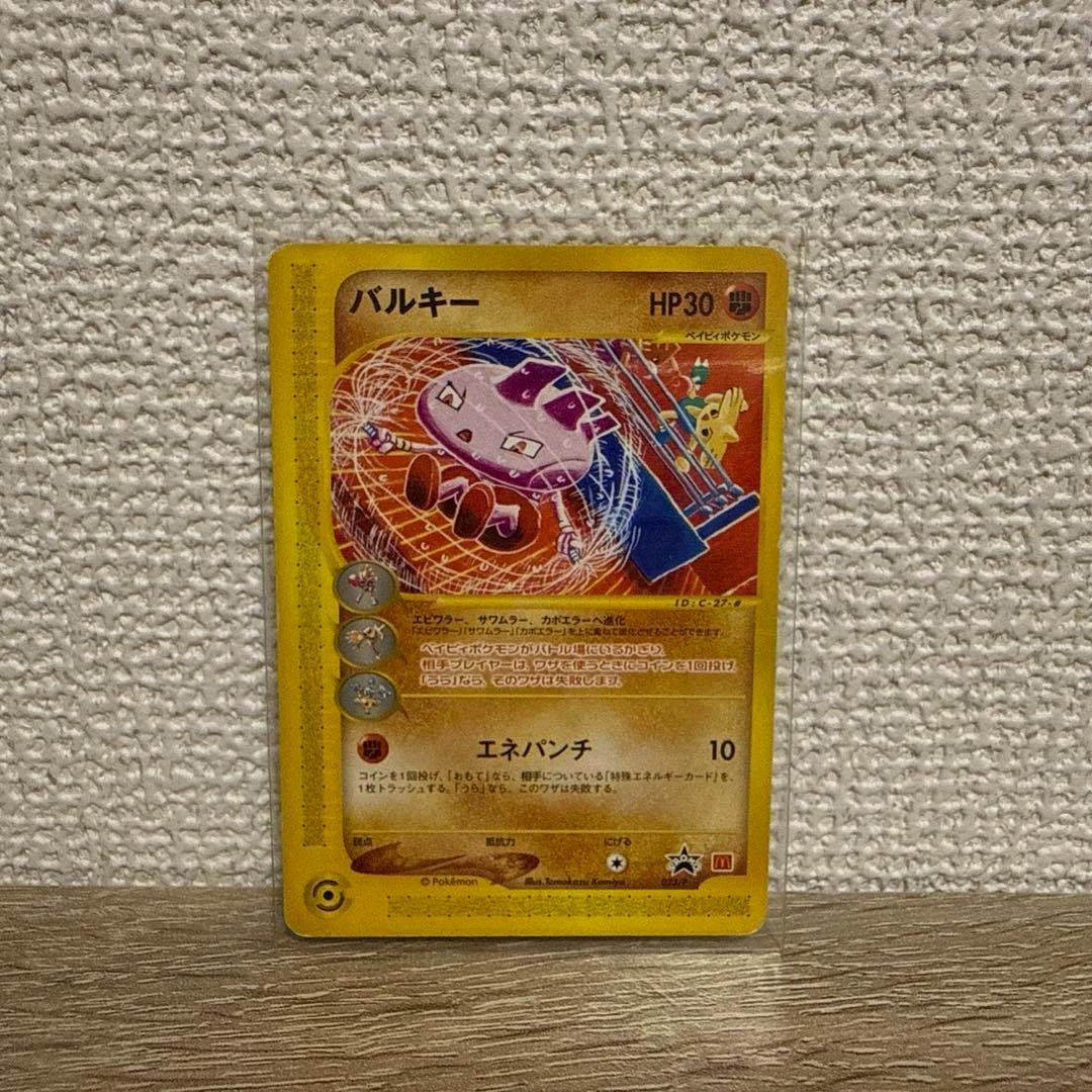 Photograph of the front of the Japanese Pokémon trading card バルキー in a clear sleeve showing the artwork, Japanese text, and HP30 against a textured wall.