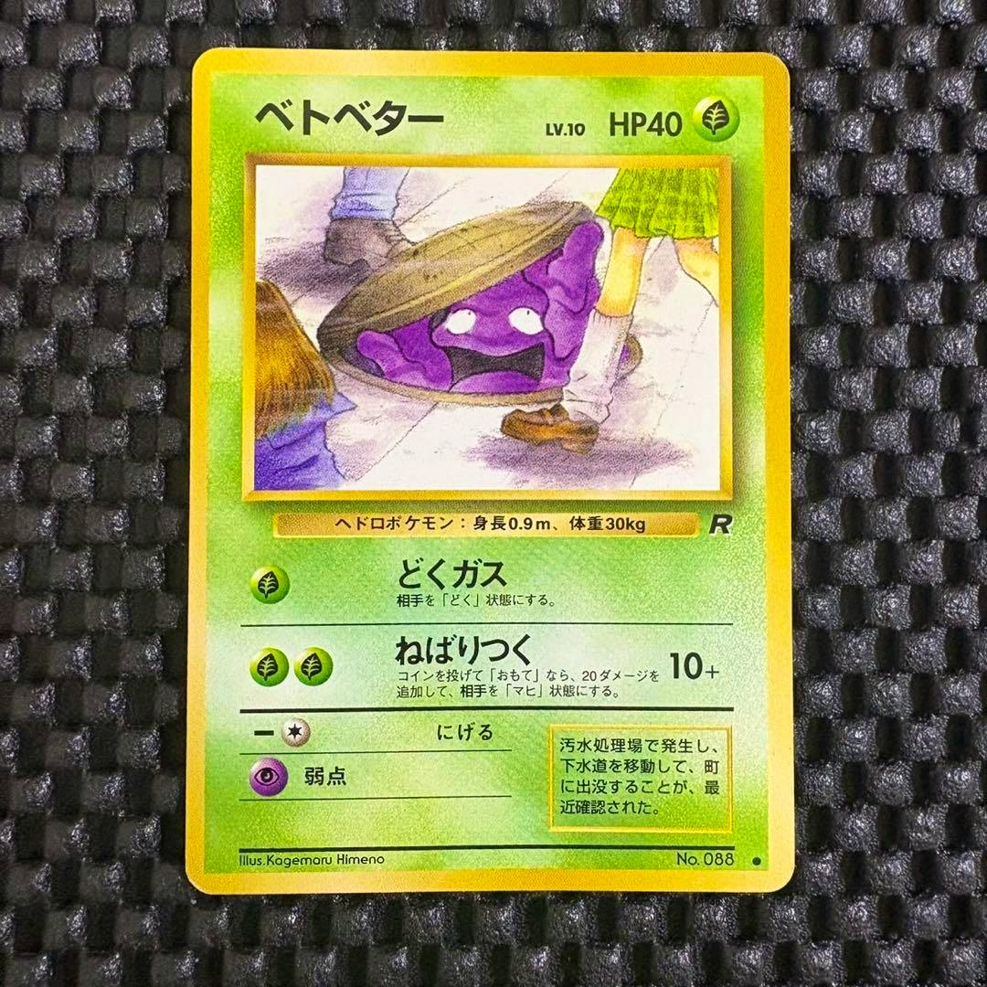 Photograph of a Japanese Pokémon trading card showing ベトベター (Grimer) placed on a black textured background.