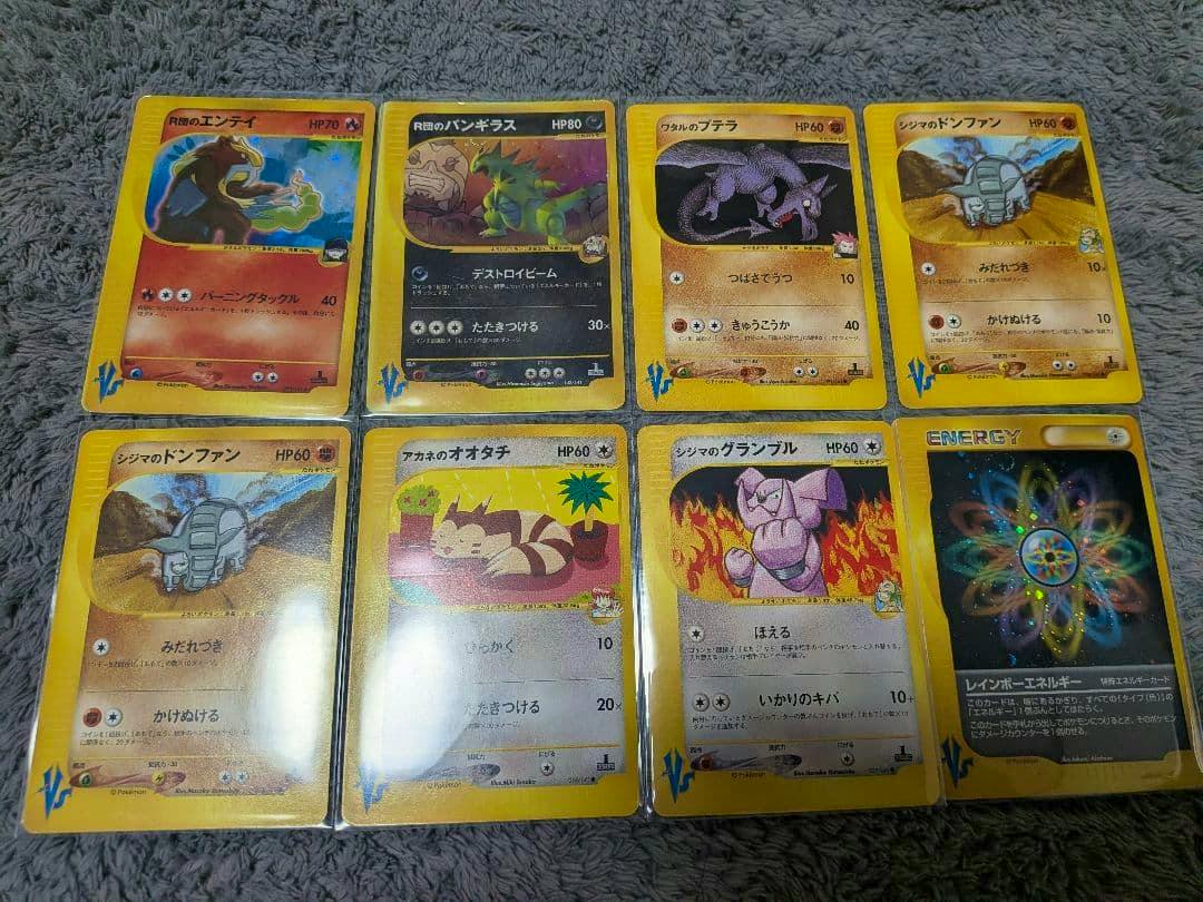 Eight Pokémon VS series trading cards shown face-up in two rows on a gray textured surface.