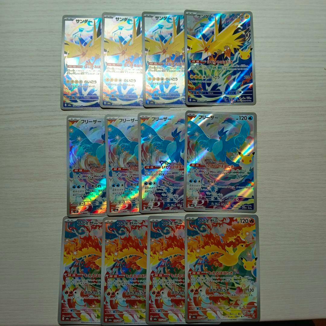 Twelve holographic Pokémon cards (サンダー/フリーザー/ファイヤー) arranged in three rows on a light wood surface.