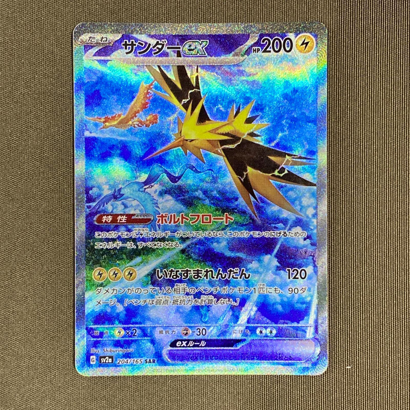 Close-up photo of the Pokémon trading card サンダーex (SV2a 204/165 SAR) face-up on a fabric background.