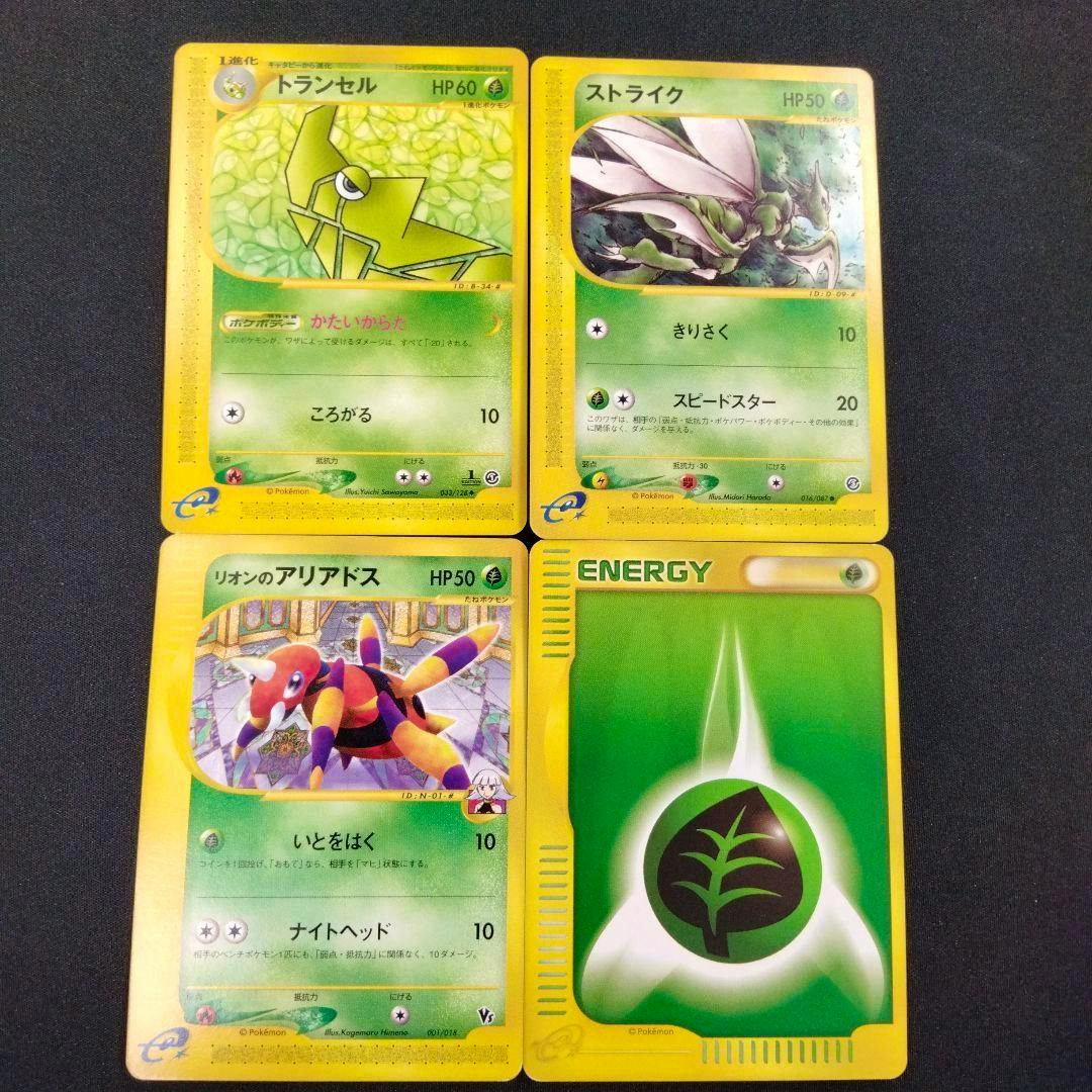 Four trading cards (トランセル, ストライク, アリアドス) plus a Grass Energy card shown face-up in a 2x2 arrangement on a dark background.