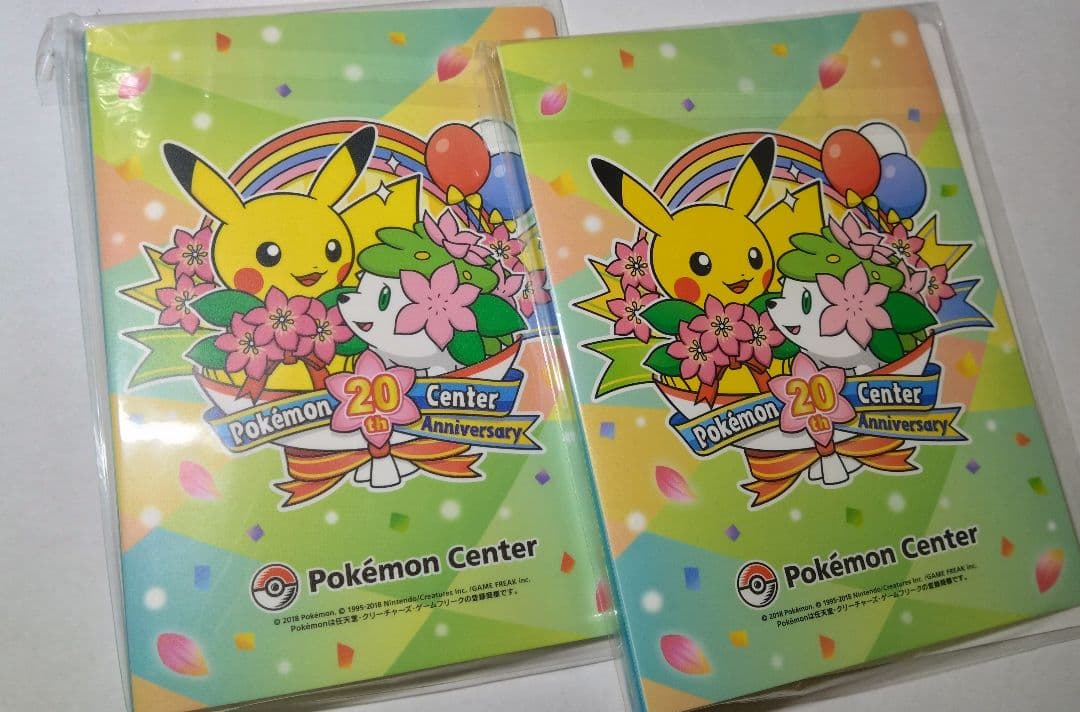 Two Pokémon Center 20th Anniversary photo albums featuring Pikachu and Shaymin artwork, shown in plastic sleeves on a white background.