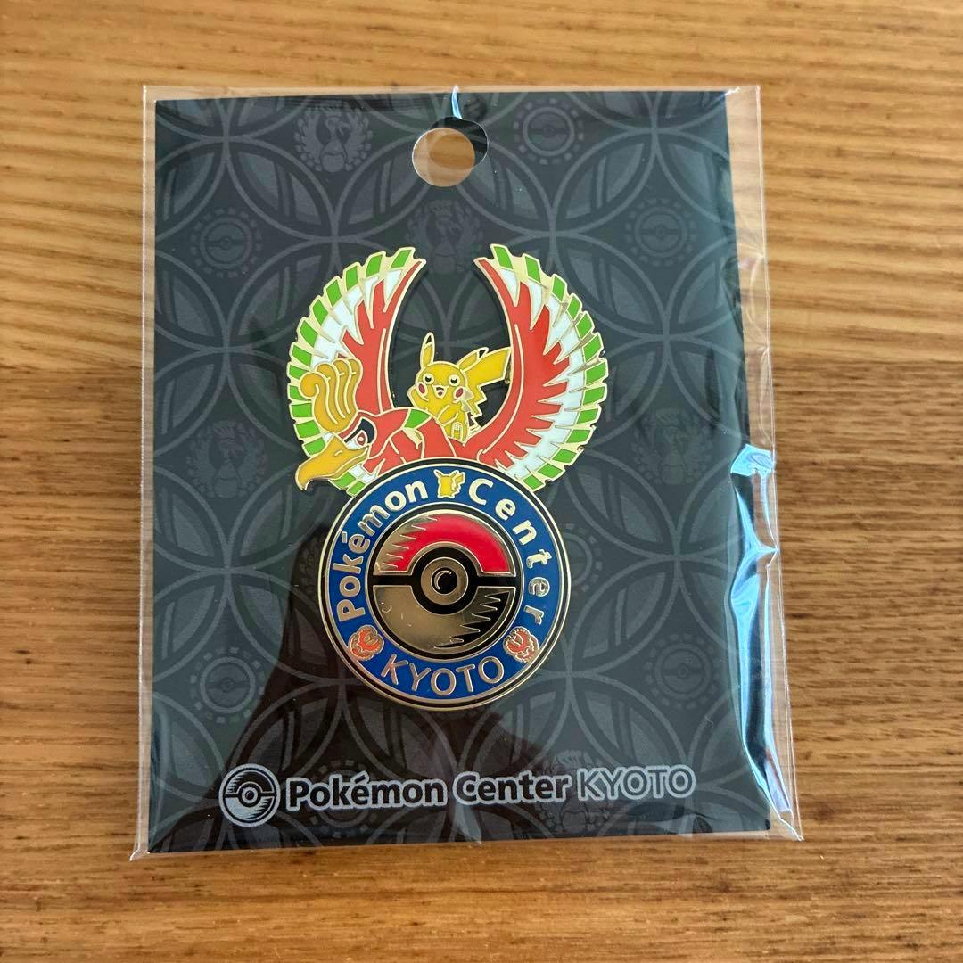 Front photo of the Pokémon Center Kyoto pin badge in its plastic packaging, showing a colorful pin with Pikachu riding a large winged bird above a Poké Ball logo on the backing card.