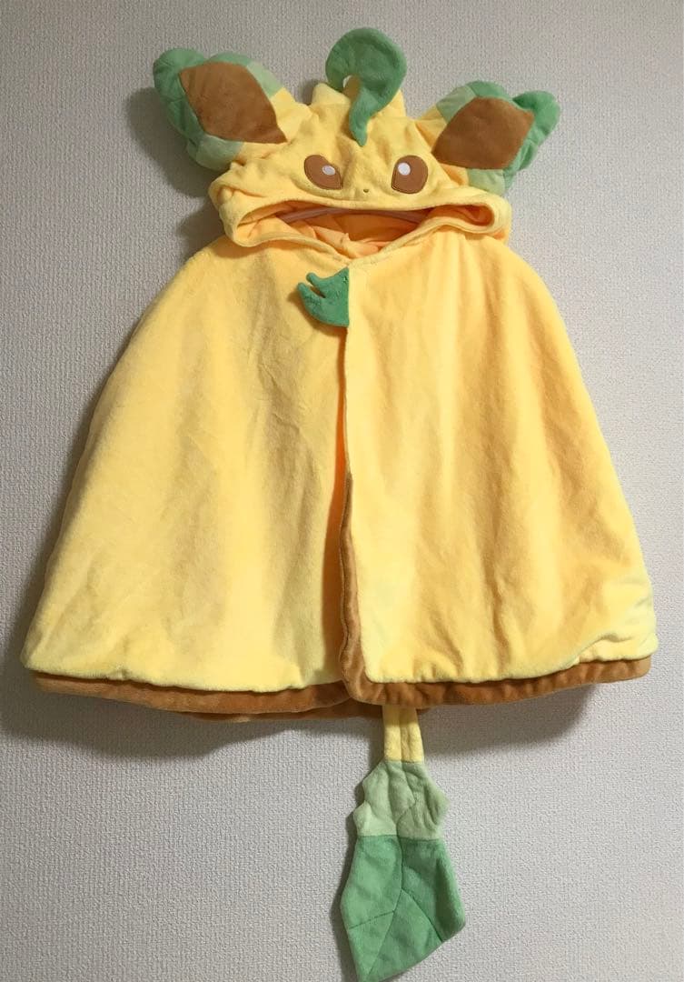 Leafeon-themed yellow hooded women's poncho with ears, face details, and a leaf tail hanging on a wall.