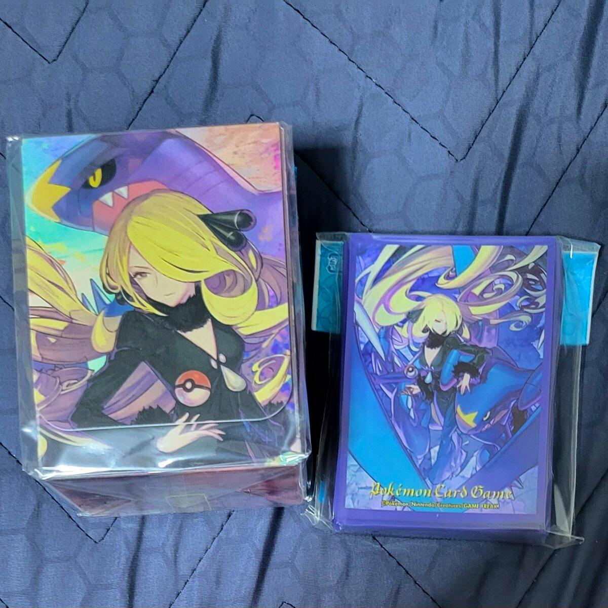 Sealed Pokémon Center deck case and matching deck sleeves featuring Cynthia and Garchomp artwork on a blue fabric background.
