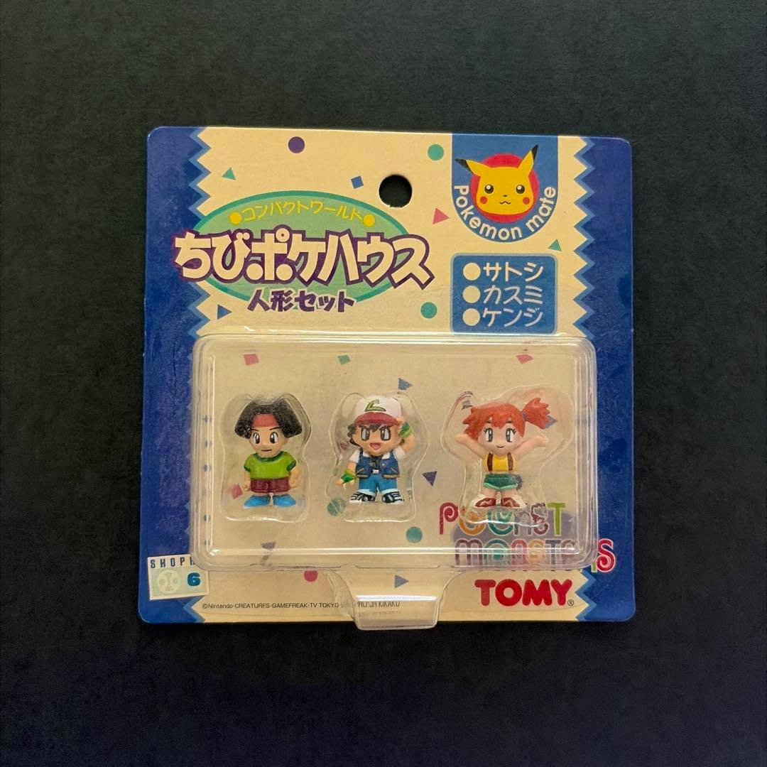 Sealed front packaging showing three small Pokémon human character figures in a blister pack with TOMY and Pokémon branding.