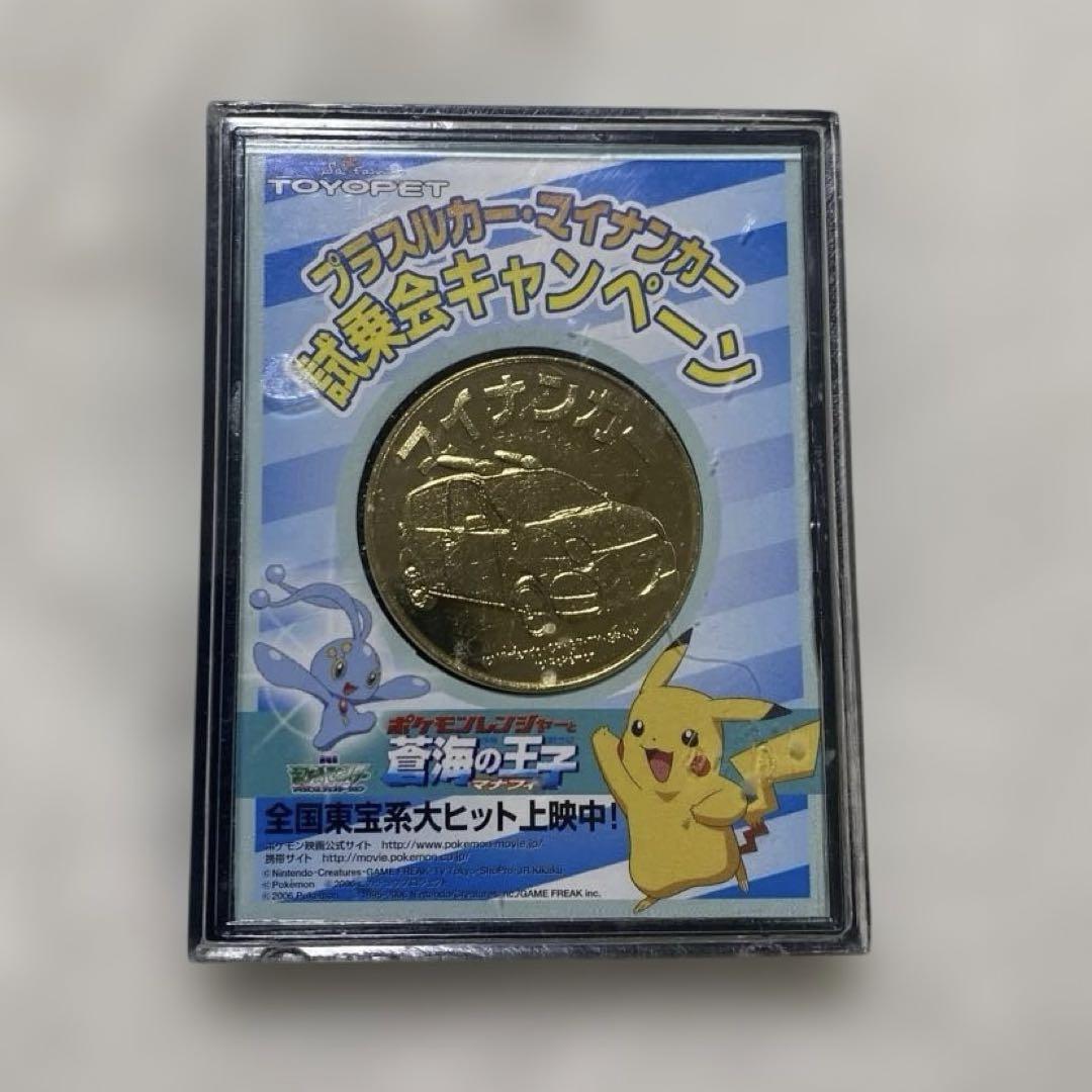 A Pokémon coin in a clear plastic display case showing Pikachu and Japanese campaign text.