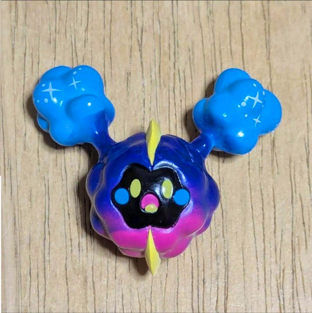 Front view of a Cosmog Pokémon plastic figure (Moncolle) placed on a wooden surface.