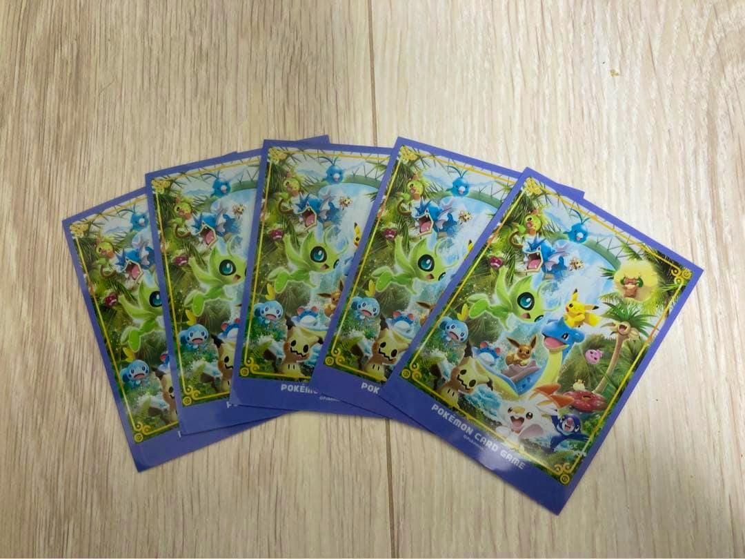 Pokémon card sleeves with colorful tropical artwork fanned on a wooden surface.