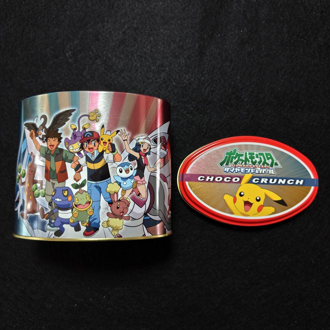 A metal Pokémon Diamond & Pearl snack tin canister with Satoshi, Pikachu, Hikari, and Takeshi printed on the side, shown with its lid.
