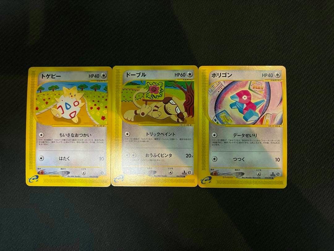 Three face-up Pokémon e trading cards showing Togepi, Drowzee, and Porygon arranged side by side on a dark textured surface.