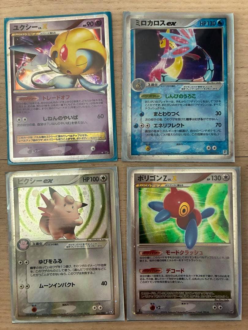 Four Pokémon ex trading cards front sides laid out in a two-by-two grid on a wooden surface.
