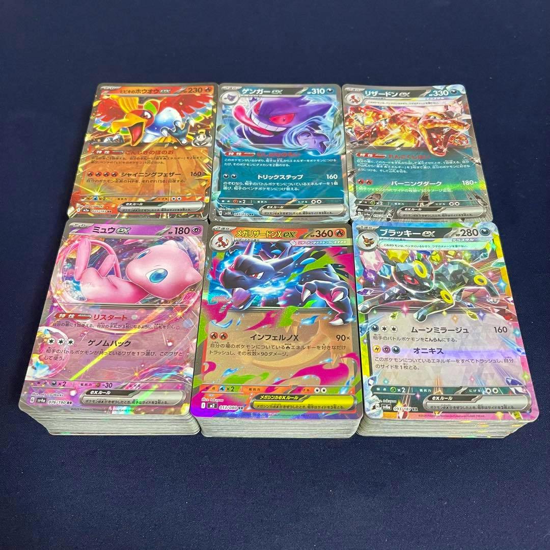 Six holographic trading cards from an ex RR bulk lot arranged in two rows on top of card stacks on a dark surface.