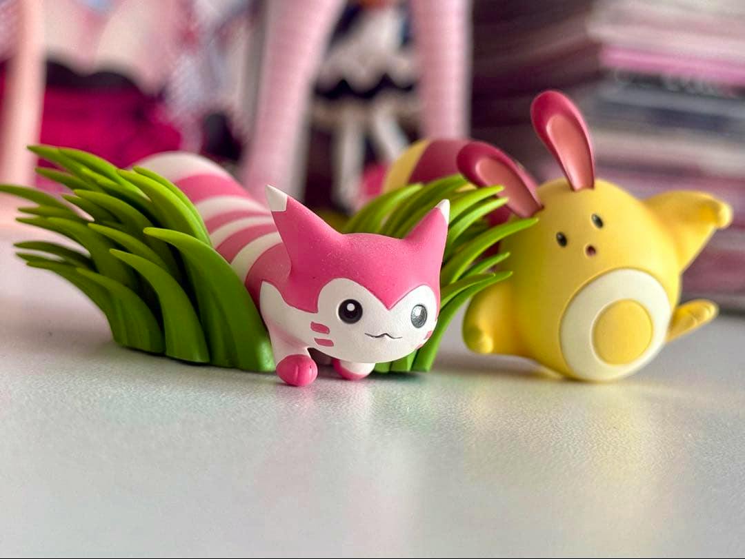 Main image shows two plastic Pokémon figures on a tabletop, including a pink-striped shiny Furret and a yellow companion figure.