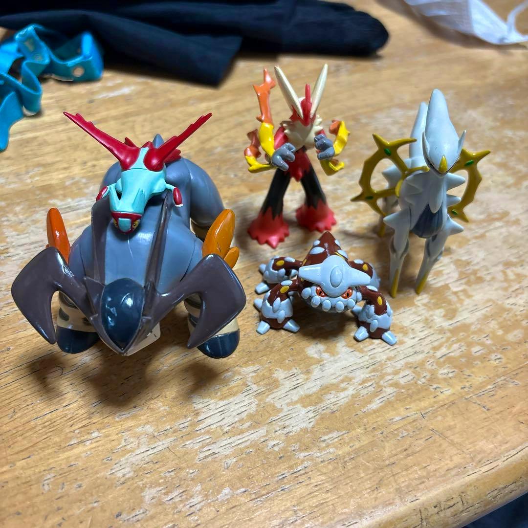 Five plastic Pokémon figures arranged on a wooden table, photographed from above and slightly front-facing.