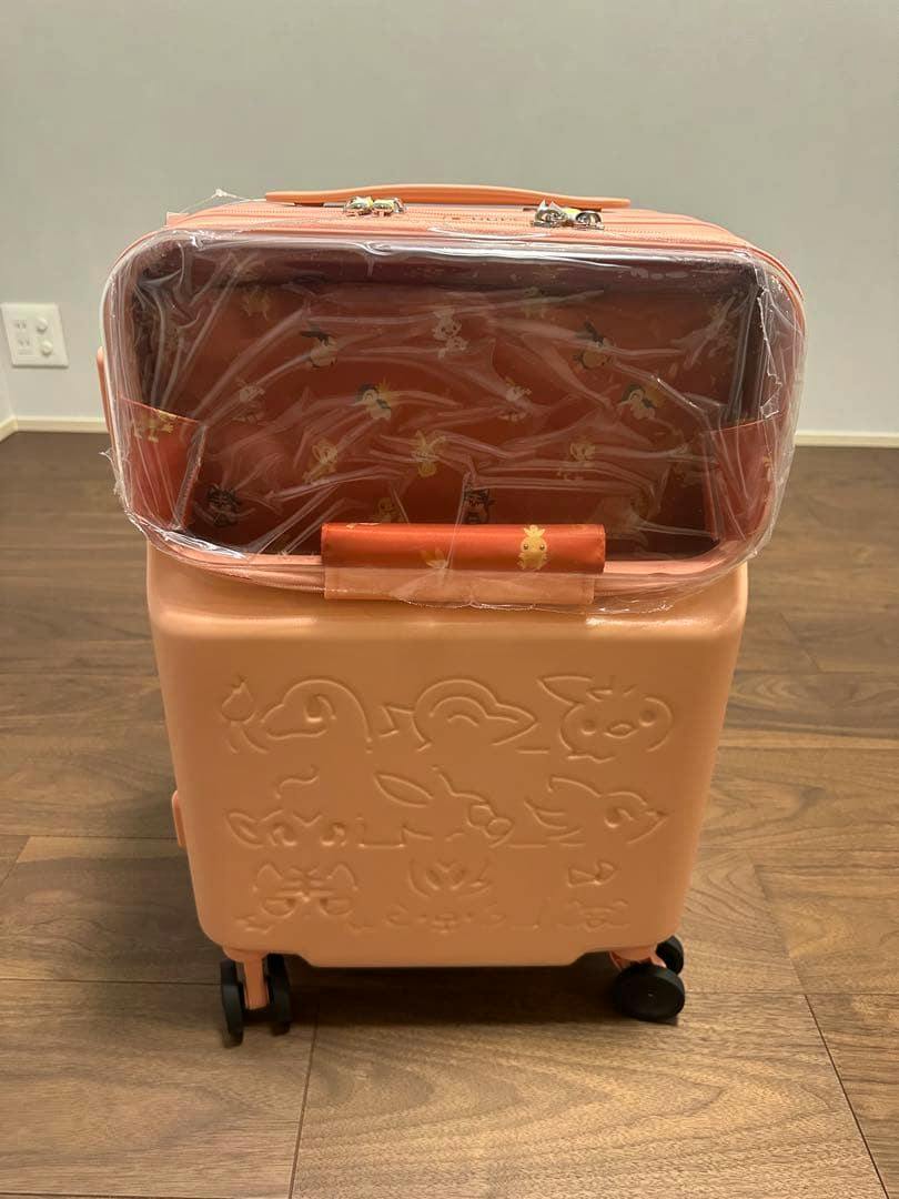 Front view of a peach-colored Pokémon front-open plastic carry case with embossed Pokémon faces and a clear top compartment covered in protective plastic.
