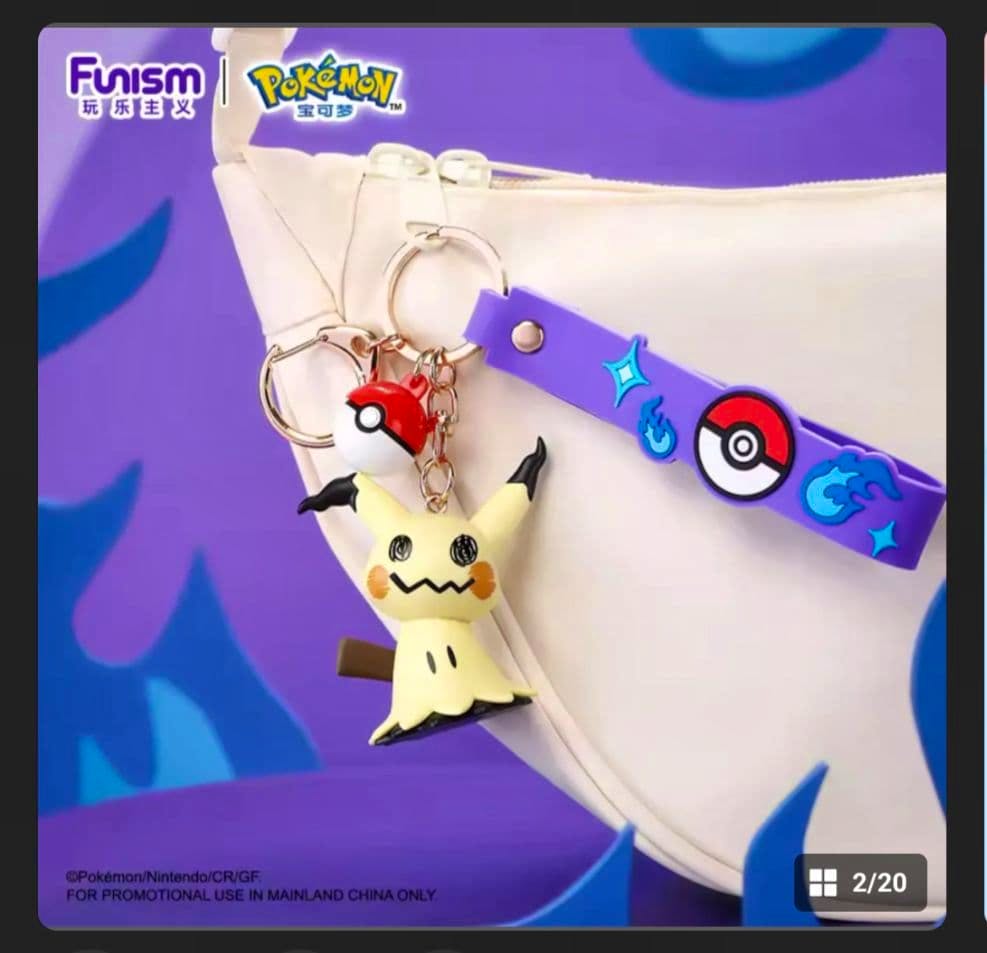A Mimikyu keychain with a small Poké Ball charm and a purple decorative strap hanging from a white bag.