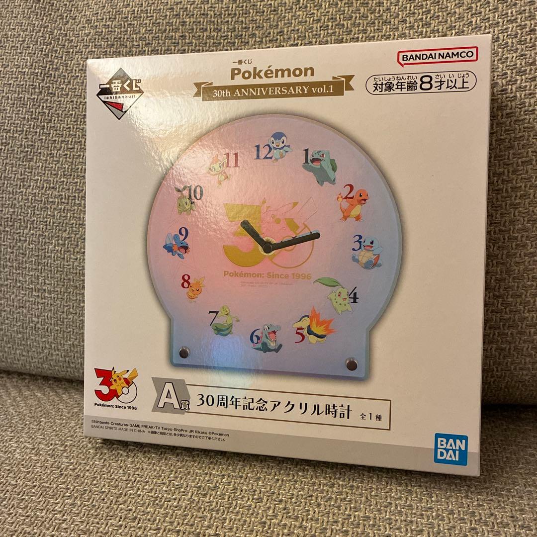 Front of boxed Pokémon 30th Anniversary acrylic wall clock (Ichiban Kuji A prize) showing the clock face and packaging.