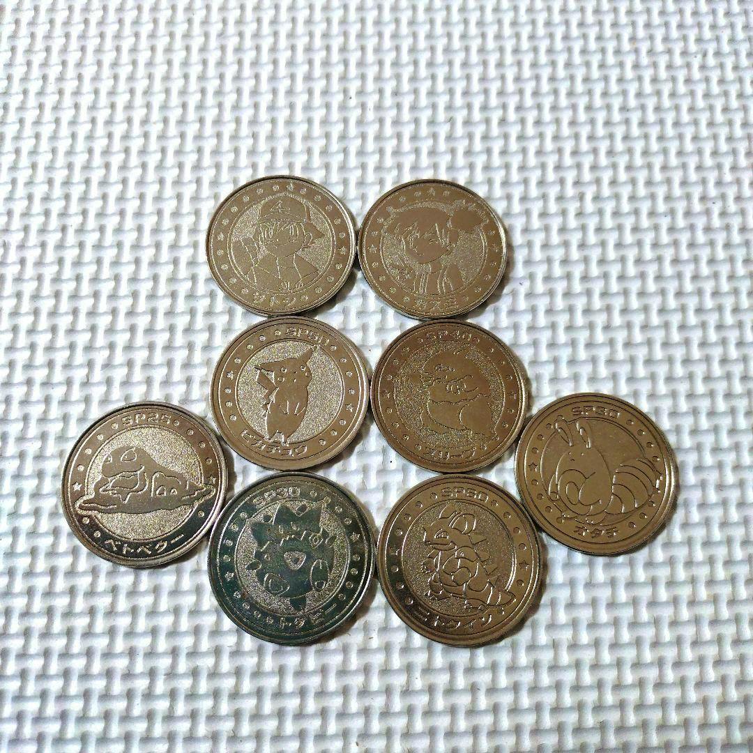 Eight Pokémon metal coins with character designs arranged on a white textured surface.