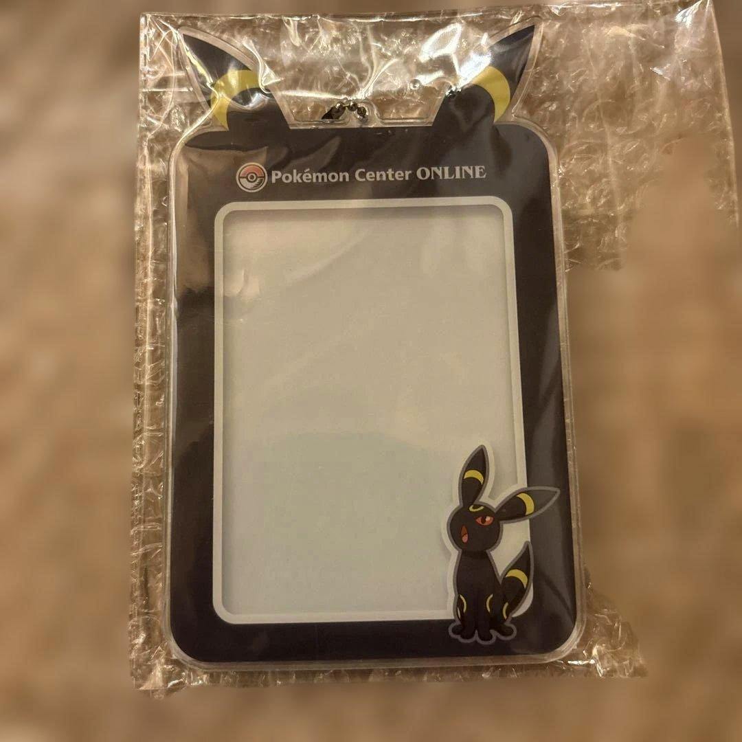 Front of an Umbreon (ブラッキー) acrylic card case in its plastic packaging, showing a clear window and the text "Pokémon Center ONLINE".