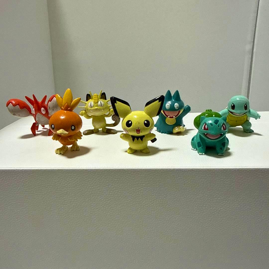 Seven Pokémon plastic figures displayed in a row on a white surface.