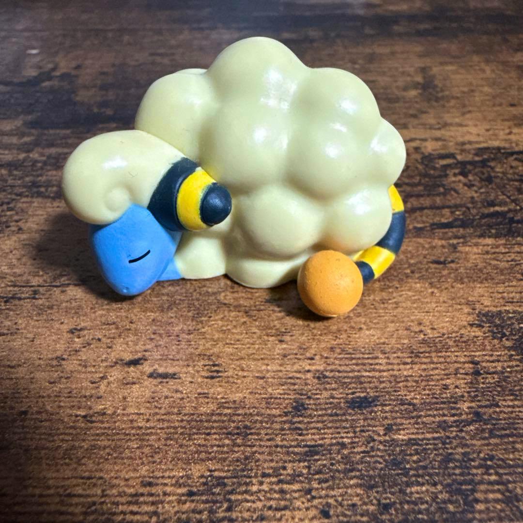 Photograph of the ポケモン おやすみフレンズ メリープ plastic figure lying asleep on a wooden surface.