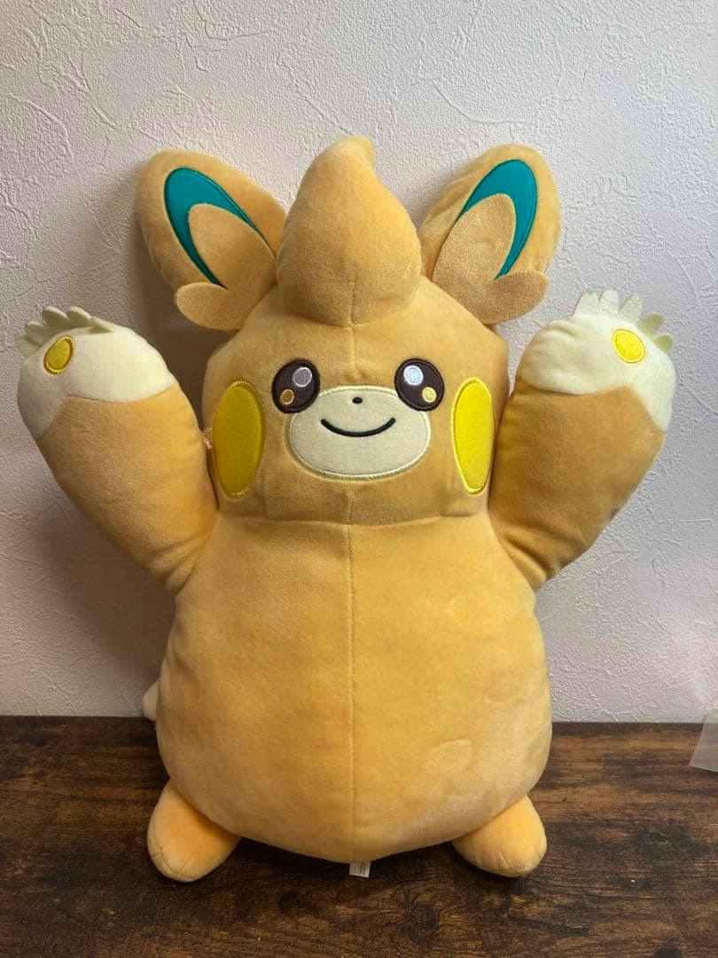 Front view of a パモット Pokémon plush toy with raised arms and a smiling face.