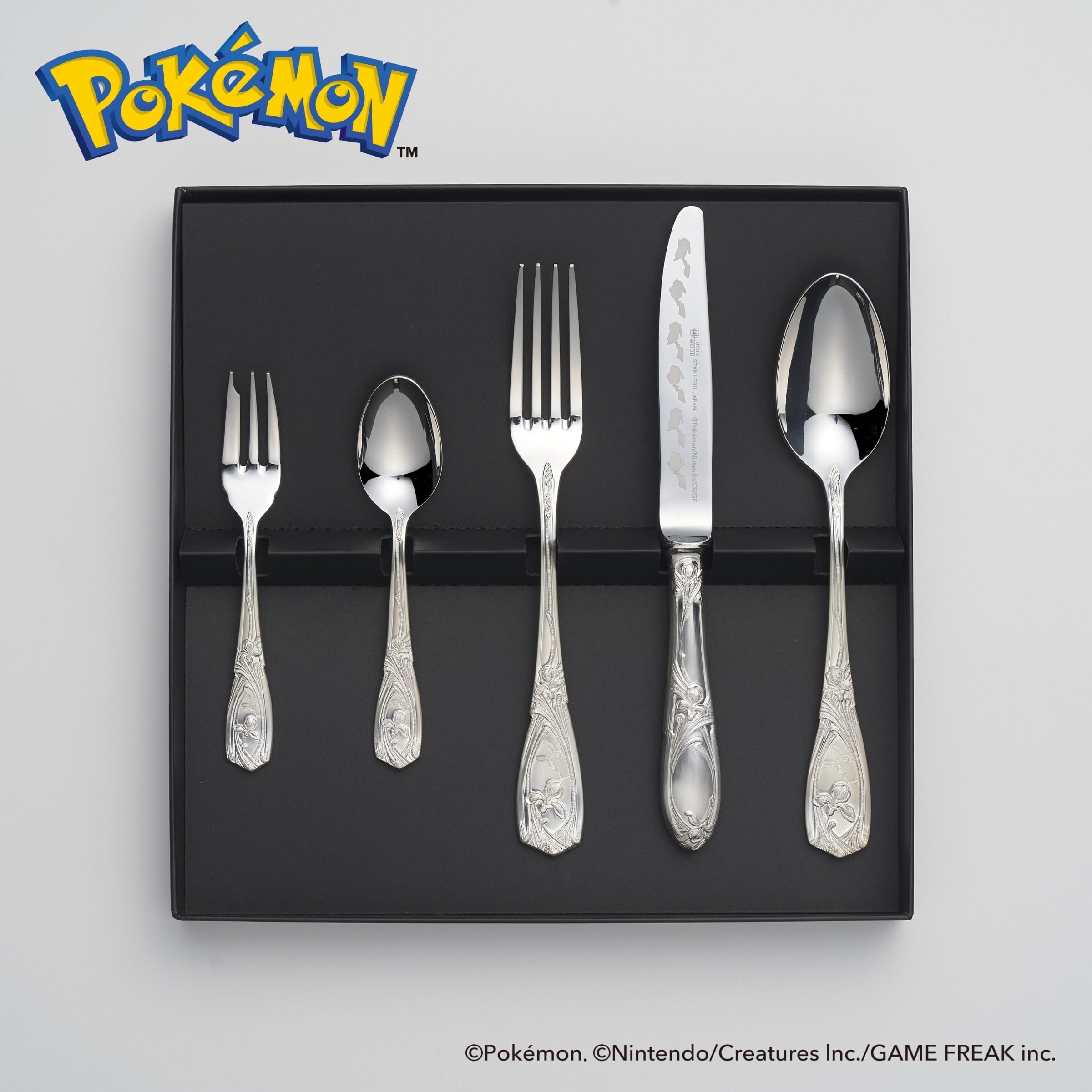 Five-piece boxed stainless steel Pokémon Pikachu personal cutlery set with two forks, two spoons, and a knife arranged in a black tray.