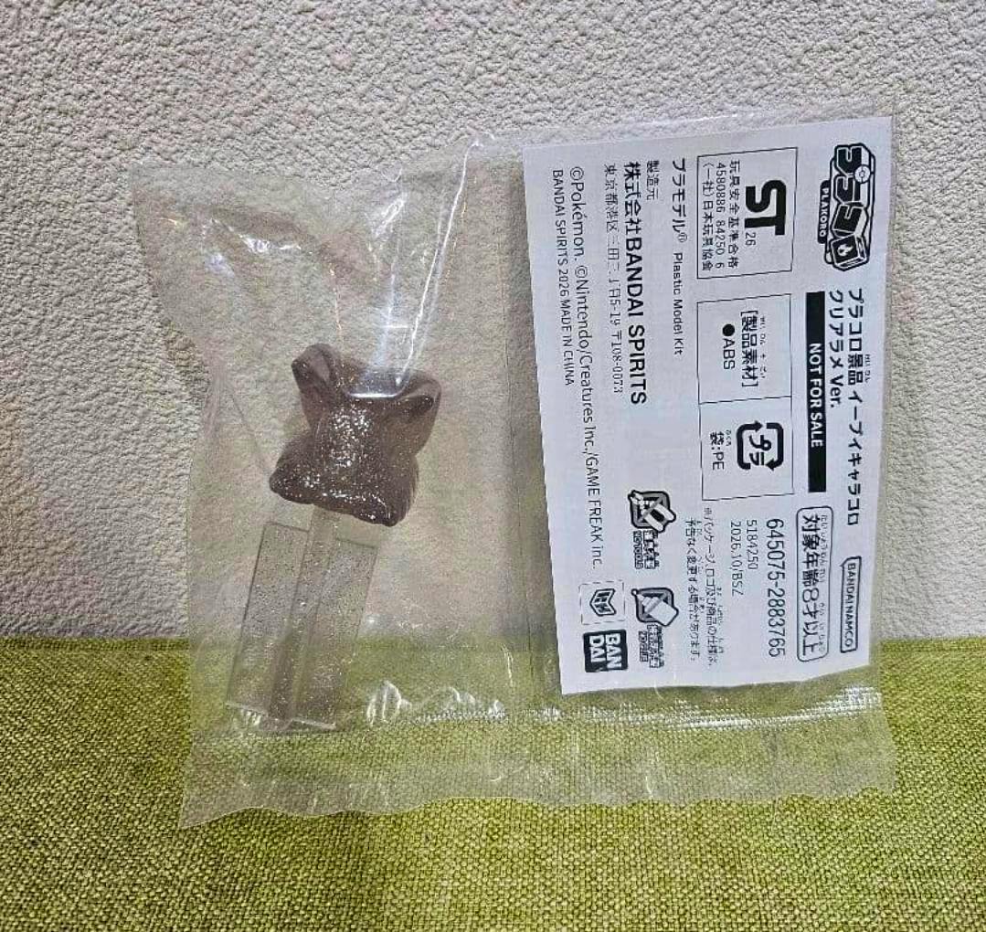 Sealed plastic bag containing a glittery Eevee figure body and two clear leg pieces with a paper instruction/label visible.