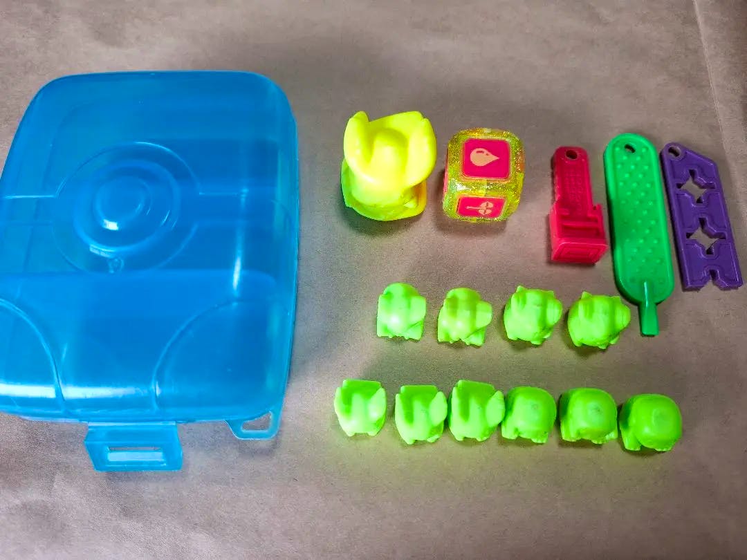 A blue plastic case and assorted small neon-green Pokémon plastic toy pieces and accessories on a flat surface.