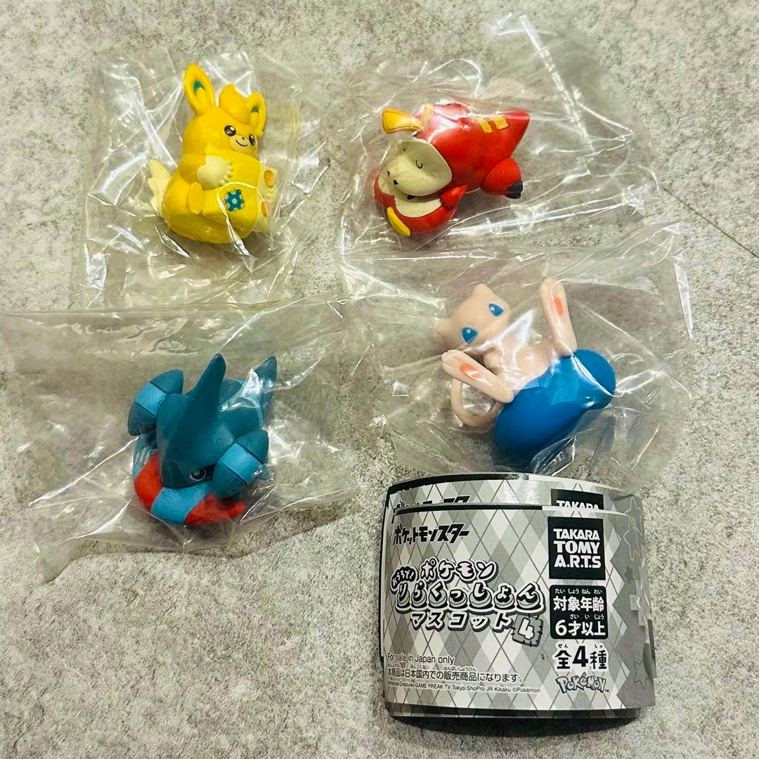 Four Pokémon mascot figures in individual plastic bags with the product paper insert, arranged on a gray surface.