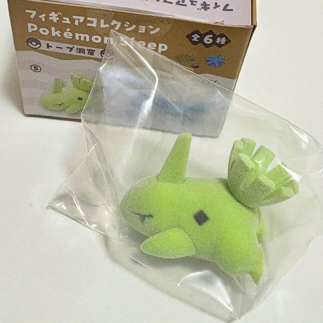 Green Larvitar (ヨーギラス) figure from the Pokémon Sleep collection shown inside a clear plastic bag with the product box visible behind.